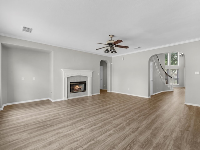 20211 Sunrise Glen Ct, Spring, TX 77379 - unfurnished living room featuring ceiling fan, arched walkways, light wood-style floors, ornamental molding, and a fireplace