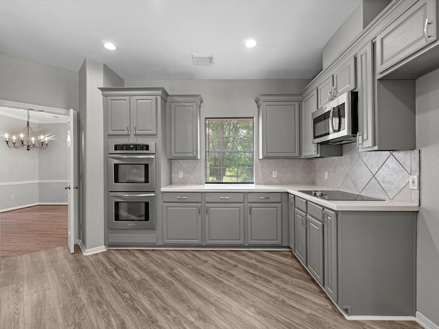 20211 Sunrise Glen Ct, Spring, TX 77379 - kitchen featuring gray cabinets, stainless steel appliances, a chandelier, light wood-style flooring, and light countertops