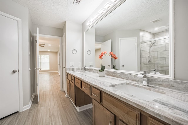 22519 Elkana Deane Ln, Katy, TX 77449 - full bathroom featuring a textured ceiling, a shower stall, wood finished floors, double vanity, and baseboards