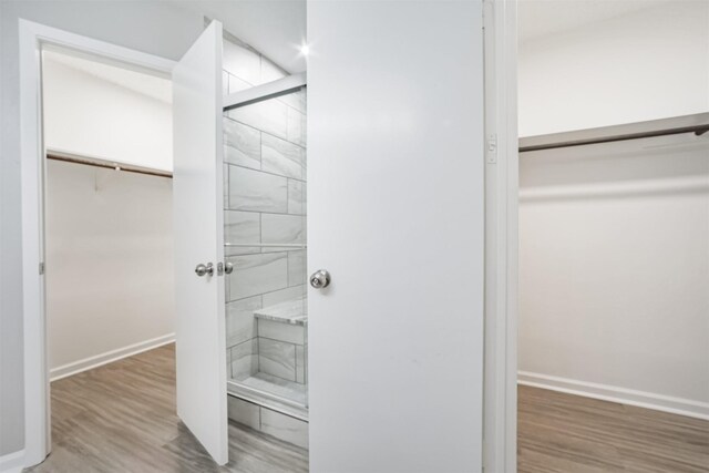 22519 Elkana Deane Ln, Katy, TX 77449 - bathroom featuring a spacious closet, baseboards, wood finished floors, and tiled shower