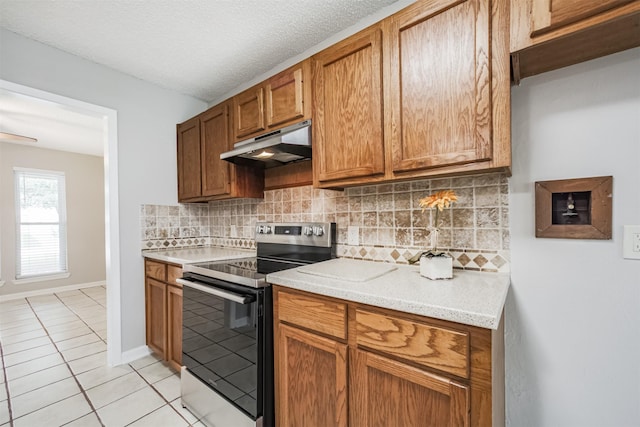 22519 Elkana Deane Ln, Katy, TX 77449 - kitchen featuring electric range, under cabinet range hood, light tile patterned floors, light countertops, and tasteful backsplash