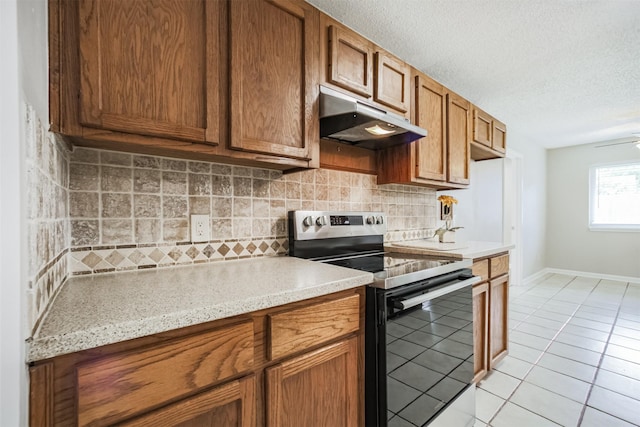 22519 Elkana Deane Ln, Katy, TX 77449 - kitchen with stainless steel range with electric stovetop, under cabinet range hood, light tile patterned floors, light countertops, and decorative backsplash