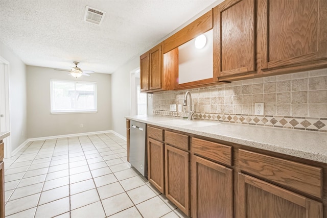 22519 Elkana Deane Ln, Katy, TX 77449 - kitchen with a sink, backsplash, brown cabinets, stainless steel dishwasher, and a textured ceiling