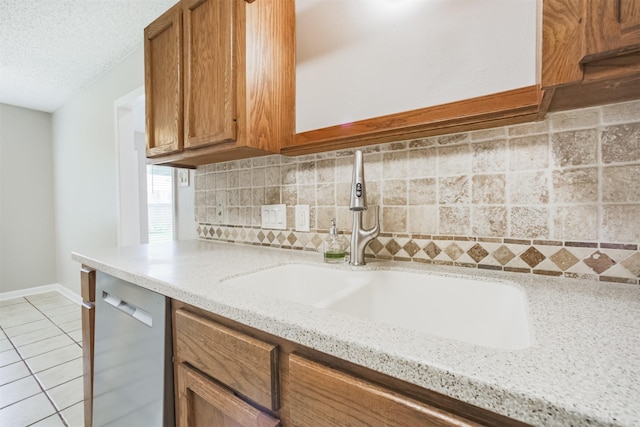 22519 Elkana Deane Ln, Katy, TX 77449 - kitchen featuring dishwasher, a sink, decorative backsplash, light tile patterned floors, and brown cabinets