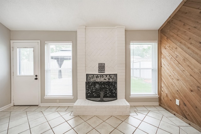 22519 Elkana Deane Ln, Katy, TX 77449 - unfurnished living room with wood walls, baseboards, light tile patterned floors, a textured ceiling, and a fireplace