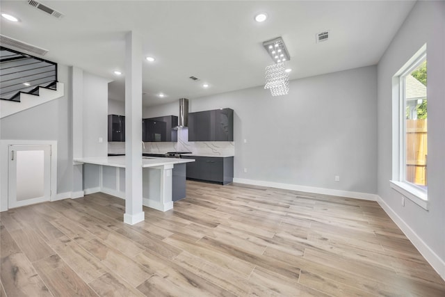 4923 Golden Forest St Unit A, Houston, TX 77091 - kitchen featuring wall chimney range hood, light countertops, light wood-style floors, a peninsula, and recessed lighting