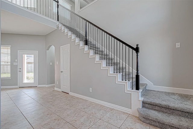 30806 Academy Trace Dr, Spring, TX 77386 - stairs featuring arched walkways, baseboards, tile patterned floors, and a towering ceiling