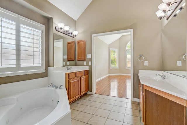 10502 Ginger Gln, Missouri City, TX 77459 - full bath with vaulted ceiling, tile patterned flooring, a tub with jets, two vanities, and baseboards