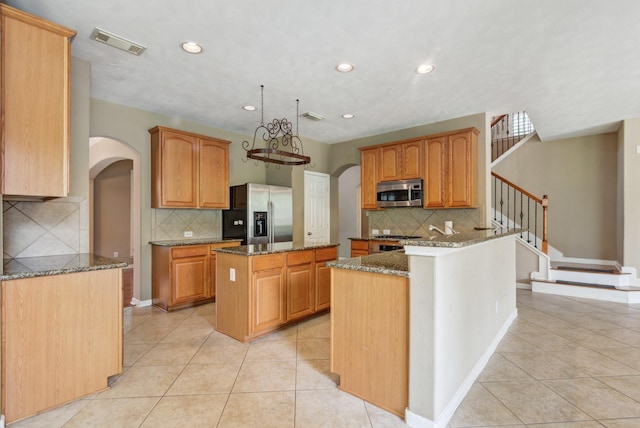 10502 Ginger Gln, Missouri City, TX 77459 - kitchen featuring appliances with stainless steel finishes, arched walkways, light tile patterned floors, and recessed lighting