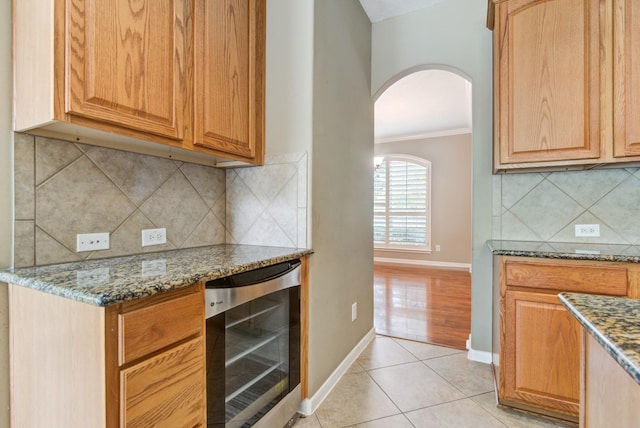 10502 Ginger Gln, Missouri City, TX 77459 - kitchen featuring beverage cooler, arched walkways, ornamental molding, dark stone countertops, and baseboards
