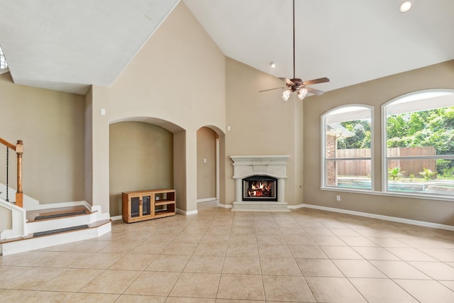 10502 Ginger Gln, Missouri City, TX 77459 - unfurnished living room featuring light tile patterned flooring, ceiling fan, a lit fireplace, stairs, and baseboards