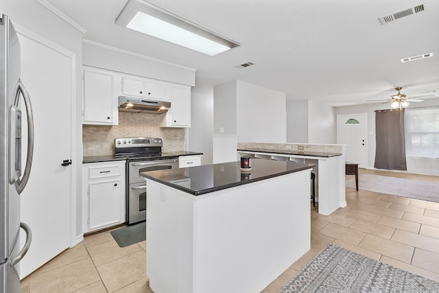 36 Jamaica Ln, Normangee, TX 77871 - kitchen with under cabinet range hood, appliances with stainless steel finishes, light tile patterned flooring, a center island, and white cabinetry