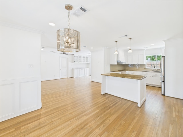 4927 Ward St, Houston, TX 77021 - kitchen with freestanding refrigerator, a sink, a chandelier, ornamental molding, and white cabinetry