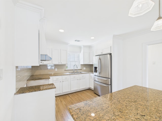 4927 Ward St, Houston, TX 77021 - kitchen featuring stainless steel fridge with ice dispenser, a sink, light wood-style floors, white cabinets, and backsplash