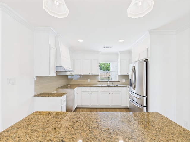 4927 Ward St, Houston, TX 77021 - kitchen featuring stainless steel fridge with ice dispenser, a sink, white cabinets, premium range hood, and ornamental molding