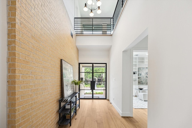 3851 Merrick St, Houston, TX 77025 - entrance foyer with brick wall, a towering ceiling, wood finished floors, baseboards, and a chandelier