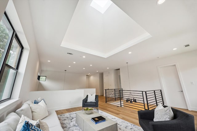 3851 Merrick St, Houston, TX 77025 - living room featuring light wood-type flooring, recessed lighting, a skylight, and a tray ceiling