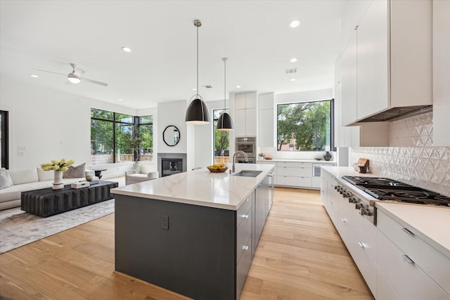 3851 Merrick St, Houston, TX 77025 - kitchen featuring stainless steel gas cooktop, modern cabinets, a glass covered fireplace, plenty of natural light, and recessed lighting