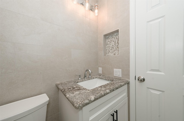 9607 Rumbling Wood Ln, Houston, TX 77086 - half bathroom featuring toilet, tile walls, and vanity