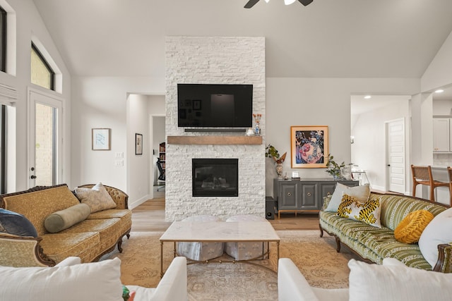 19002 Valentine Padlock Cir, Tomball, TX 77377 - living area with light wood finished floors, a ceiling fan, a stone fireplace, high vaulted ceiling, and recessed lighting