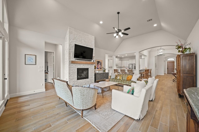 19002 Valentine Padlock Cir, Tomball, TX 77377 - living room with a stone fireplace, ceiling fan, light wood finished floors, arched walkways, and recessed lighting