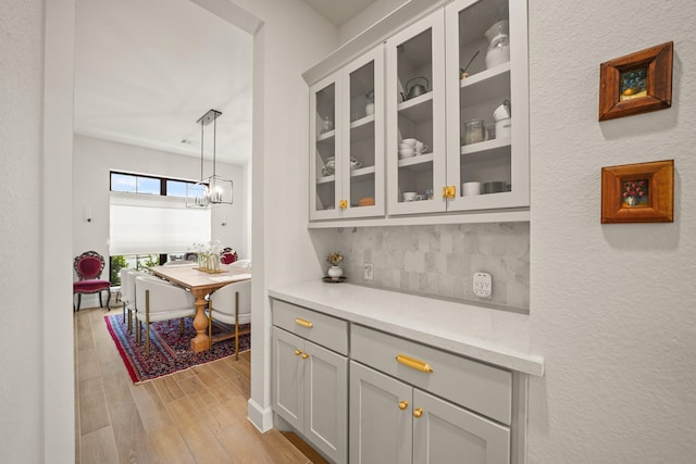 19002 Valentine Padlock Cir, Tomball, TX 77377 - bar with decorative backsplash, light wood-style floors, and decorative light fixtures