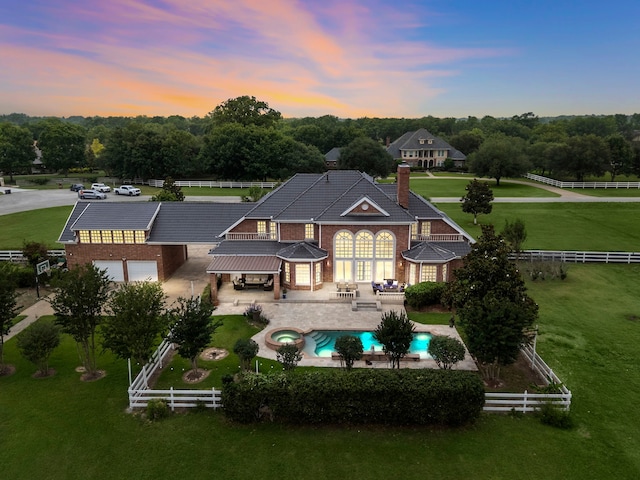 3818 Foolish Pleasure Ct, Richmond, TX 77406 - back of house at dusk with a chimney, brick siding, a patio, and a pool with connected hot tub