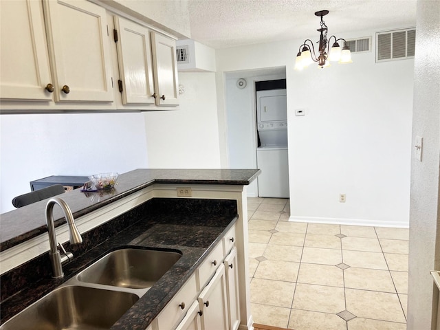12550 Whittington Dr Unit 712, Houston, TX 77077 - kitchen with stacked washer / drying machine, a sink, dark stone counters, light tile patterned floors, and a textured ceiling