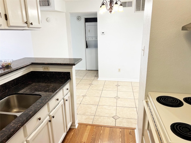 12550 Whittington Dr Unit 712, Houston, TX 77077 - kitchen featuring stacked washer / dryer, dark stone countertops, white electric range, white cabinets, and a chandelier