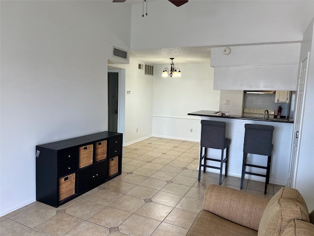 12550 Whittington Dr Unit 712, Houston, TX 77077 - kitchen with dark countertops, a chandelier, ceiling fan, light tile patterned floors, and a breakfast bar