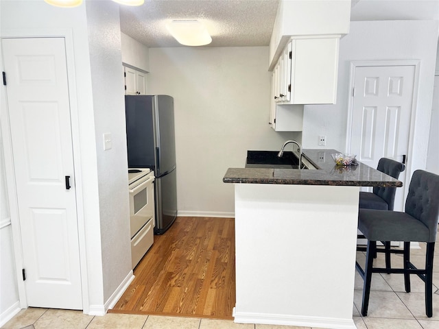 12550 Whittington Dr Unit 712, Houston, TX 77077 - kitchen featuring white electric range, a peninsula, a breakfast bar area, white cabinets, and a textured ceiling