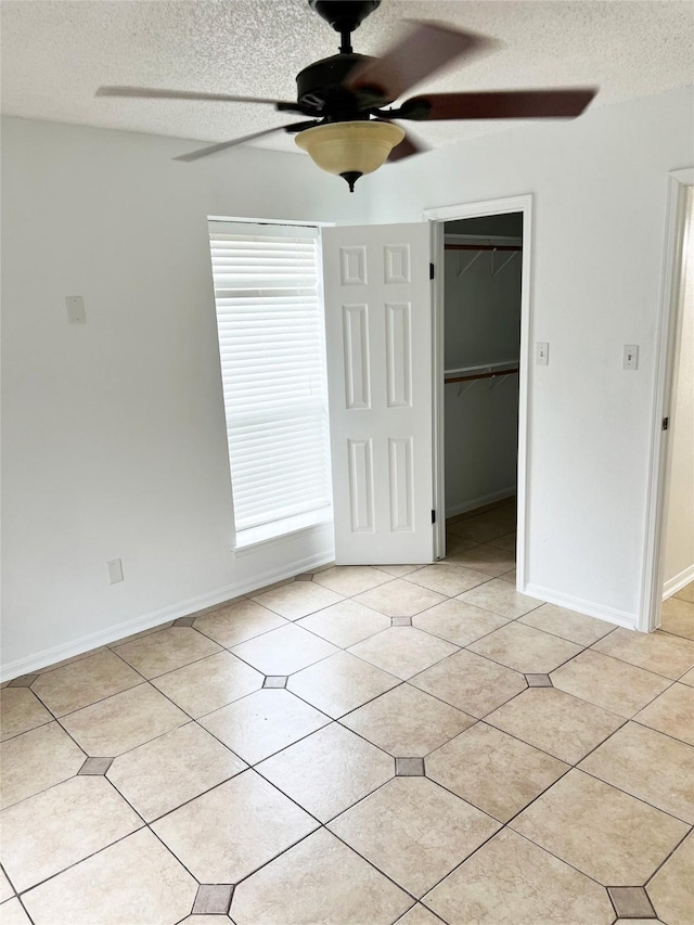 12550 Whittington Dr Unit 712, Houston, TX 77077 - unfurnished bedroom with a textured ceiling, a spacious closet, ceiling fan, a closet, and light tile patterned floors