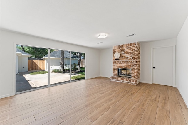 322 N Wilcrest Dr, Houston, TX 77079 - unfurnished living room featuring light wood-style flooring, a brick fireplace, and baseboards