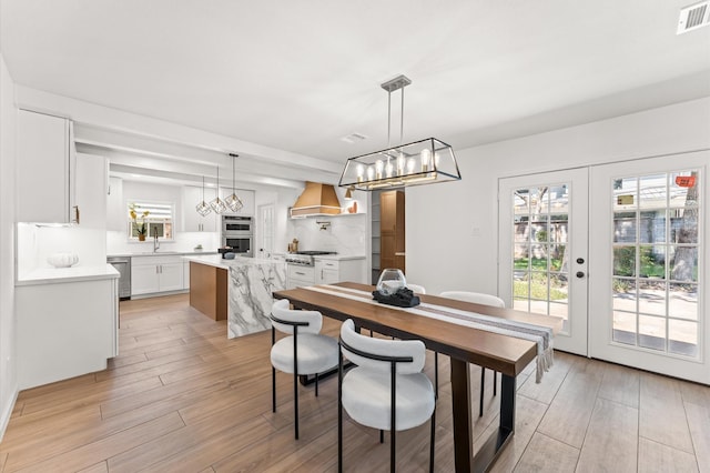 322 N Wilcrest Dr, Houston, TX 77079 - dining area featuring light wood-type flooring, a chandelier, and french doors