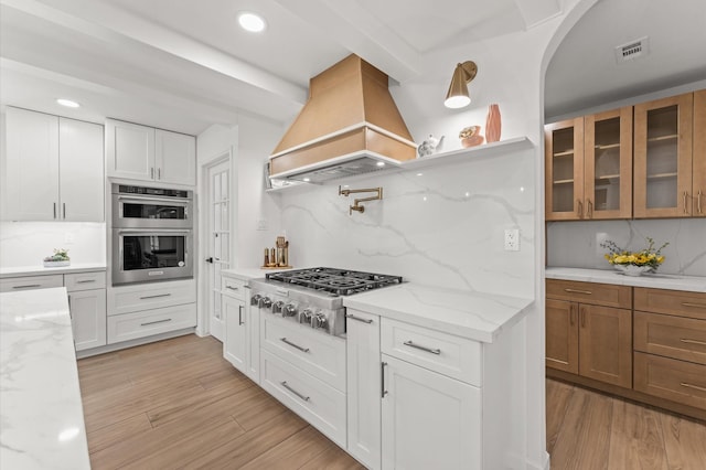 322 N Wilcrest Dr, Houston, TX 77079 - kitchen featuring custom exhaust hood, appliances with stainless steel finishes, backsplash, glass insert cabinets, and white cabinetry