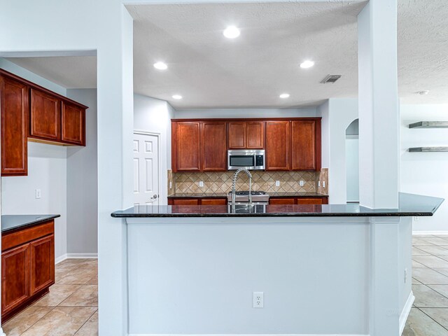 25203 Auburn Terrace Dr, Spring, TX 77389 - kitchen with stainless steel microwave, light tile patterned flooring, decorative backsplash, baseboards, and recessed lighting