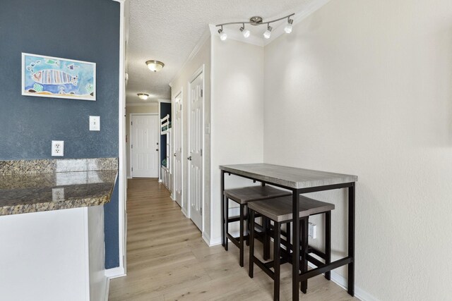 6102 Seawall Blvd Unit 260, Galveston, TX 77551 - hallway with light wood-type flooring, a textured ceiling, baseboards, and crown molding