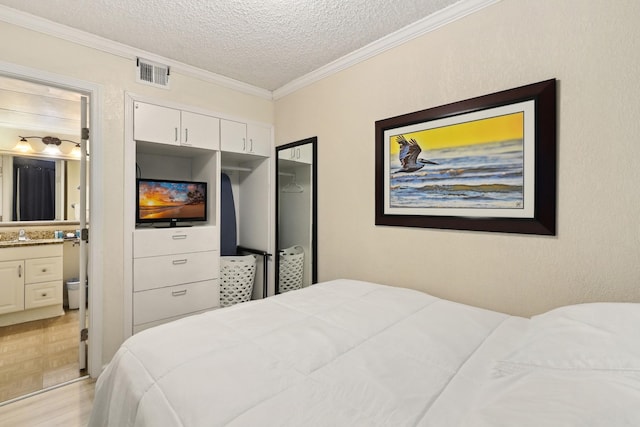 6102 Seawall Blvd Unit 260, Galveston, TX 77551 - bedroom featuring a textured ceiling, crown molding, ensuite bath, parquet flooring, and a closet