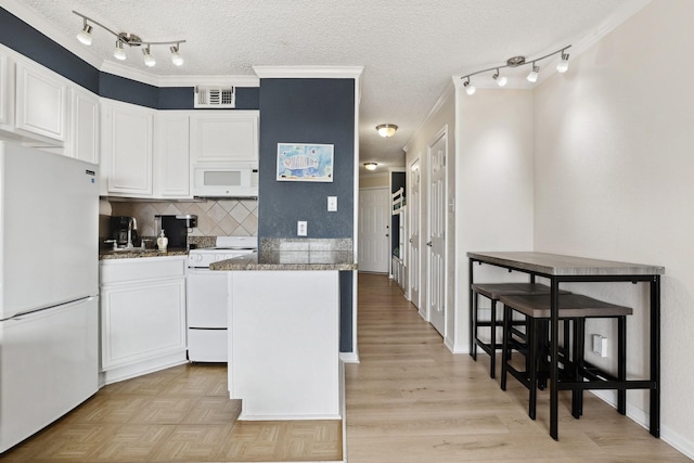 6102 Seawall Blvd Unit 260, Galveston, TX 77551 - kitchen with white appliances, a textured ceiling, white cabinets, backsplash, and rail lighting