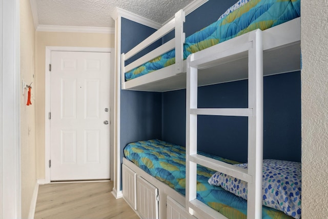 6102 Seawall Blvd Unit 260, Galveston, TX 77551 - bedroom with wood finished floors, ornamental molding, a textured ceiling, and baseboards