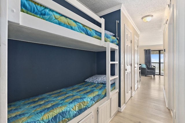 6102 Seawall Blvd Unit 260, Galveston, TX 77551 - bedroom featuring a textured ceiling, light wood-type flooring, and crown molding