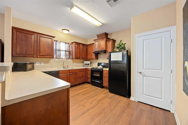 2709 Virginia St, La Marque, TX 77568 - kitchen featuring black appliances, a sink, light wood finished floors, brown cabinetry, and light countertops