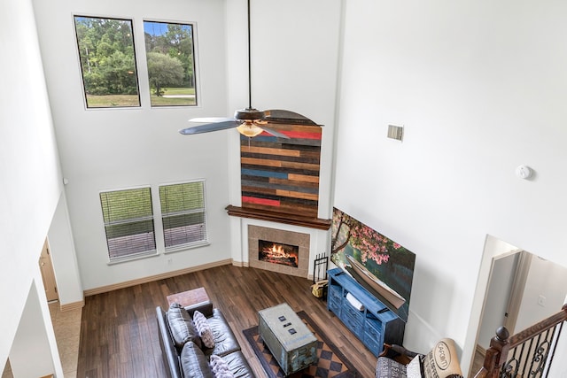 6907 Autumn Rain Ln, Spring, TX 77379 - living room featuring a towering ceiling, a tile fireplace, wood finished floors, ceiling fan, and baseboards