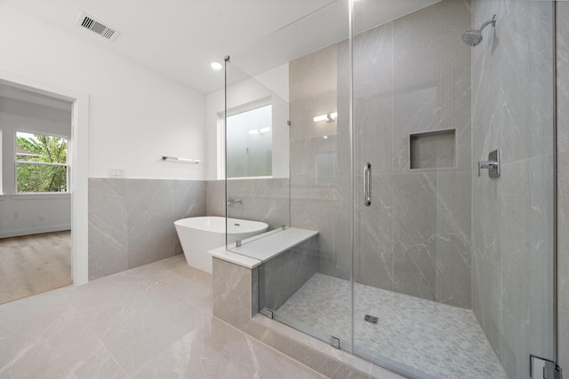 5238 Larkin St, Houston, TX 77007 - bathroom featuring a stall shower, a soaking tub, tile walls, and wainscoting