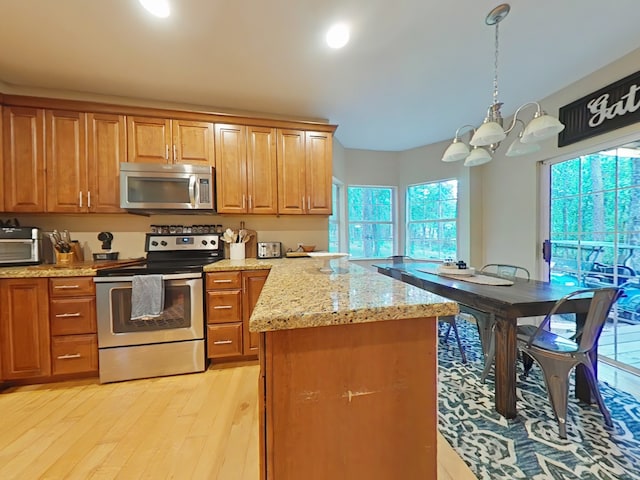 40 Dartmoor Ct, Coldspring, TX 77331 - kitchen with appliances with stainless steel finishes, a chandelier, light wood-style floors, light stone counters, and brown cabinetry