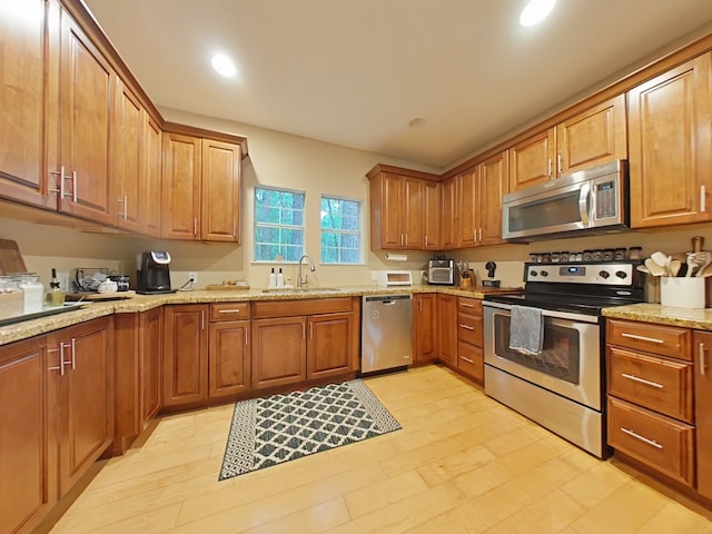40 Dartmoor Ct, Coldspring, TX 77331 - kitchen with appliances with stainless steel finishes, a sink, light stone countertops, brown cabinets, and recessed lighting