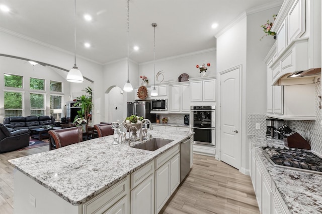 18786 Monetta Dr, New Caney, TX 77357 - kitchen featuring stainless steel appliances, arched walkways, open floor plan, a sink, and ornamental molding