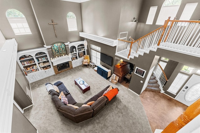 2474 Ripplewood Ct, Conroe, TX 77384 - living room with a glass covered fireplace, a high ceiling, stairs, and plenty of natural light