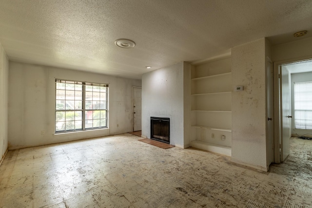 1860 White Oak Dr Unit 333, Houston, TX 77009 - unfurnished living room featuring a textured ceiling, built in features, a large fireplace, and baseboards