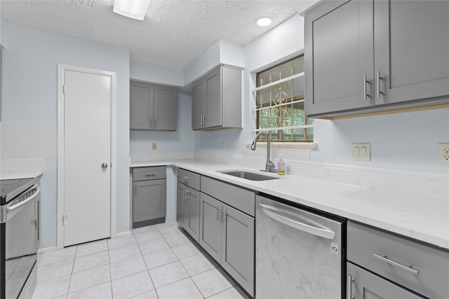 11818 Guadalupe River Dr, Houston, TX 77067 - kitchen with stainless steel appliances, gray cabinets, a sink, and a textured ceiling